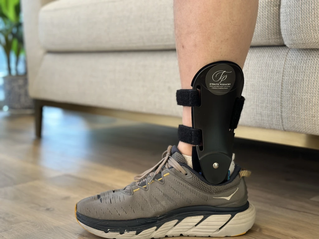 A rigid ankle brace worn over a supportive running shoe to support the inner ankle and posterior tibial tendon.