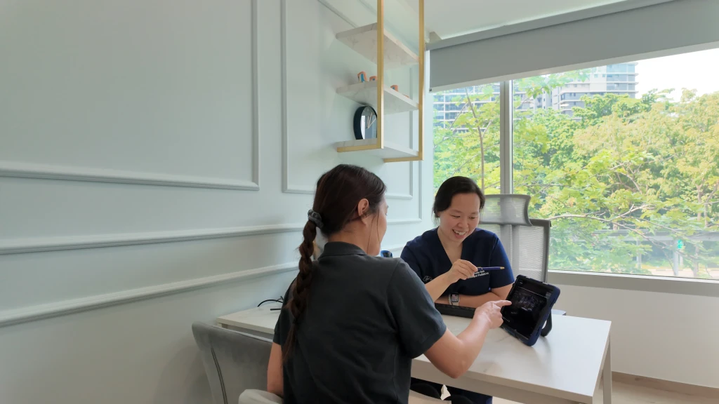 A podiatrist at Straits Podiatry reviewing a scan image on a tablet with a patient during a posterior tibial tendonitis consultation.