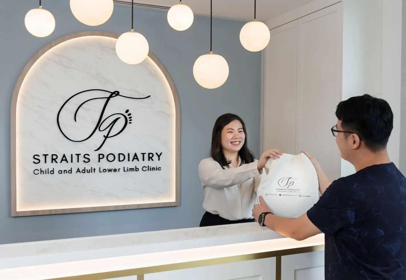 Receptionist at Straits Podiatry giving their patient his insoles and medications