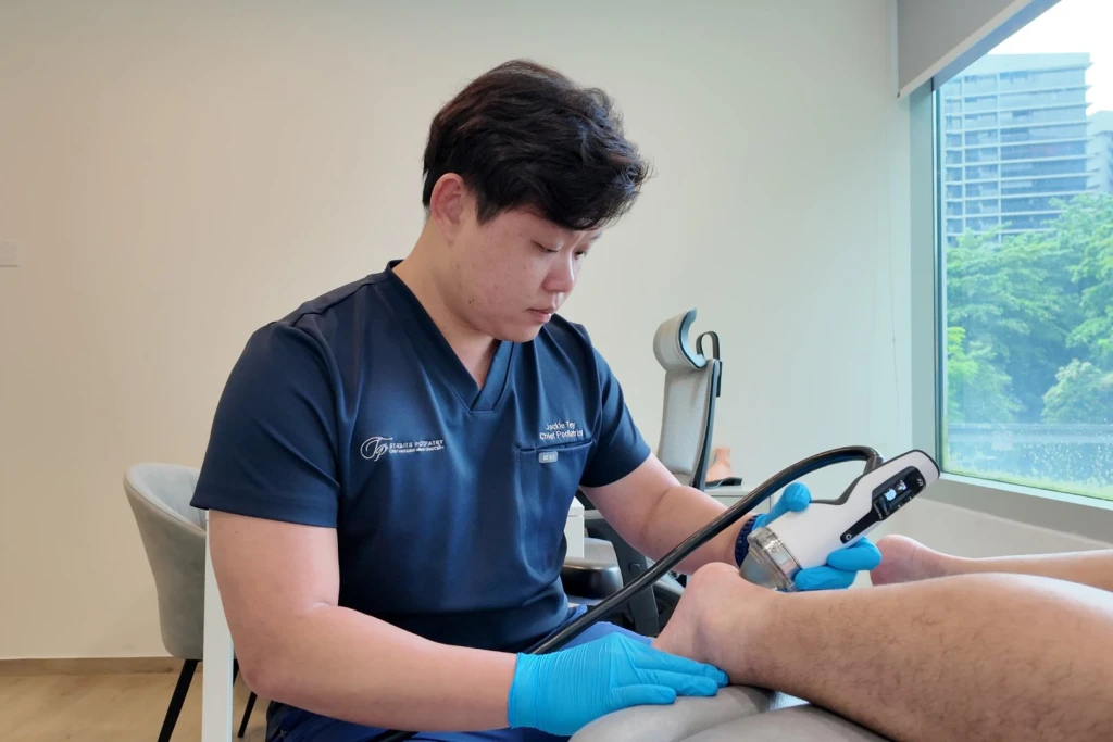 Podiatrist at Straits Podiatry delivering focused shockwave therapy (ESWT) to a patient with posterior ankle pain.