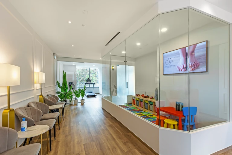 The waiting area at the Straits Podiatry Buona Vista clinic, with a glass-walled children's play corner.