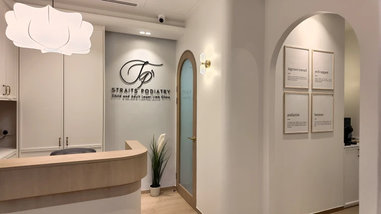 The reception at the Straits Podiatry Paya Lebar clinic, with framed foot-health word definitions on the wall.