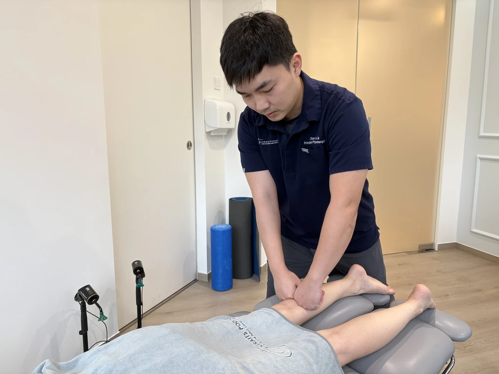 Mr Chan Lai Jie performing manual therapy on a patient's lower leg in the physiotherapy treatment room.
