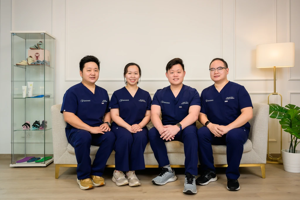 The four podiatrists of Straits Podiatry seated together in the clinic: Mr Daniel Wong, Ms Michelle Goh, Mr Jackie Tey, and Mr Benedict Khoo.
