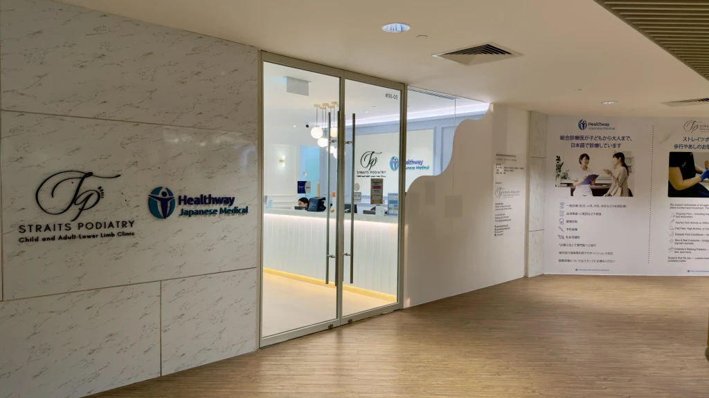 The Orchard clinic entrance at unit 06-05 with marble walls, glass doors, and a Japanese-language information panel for Healthway Japanese Medical