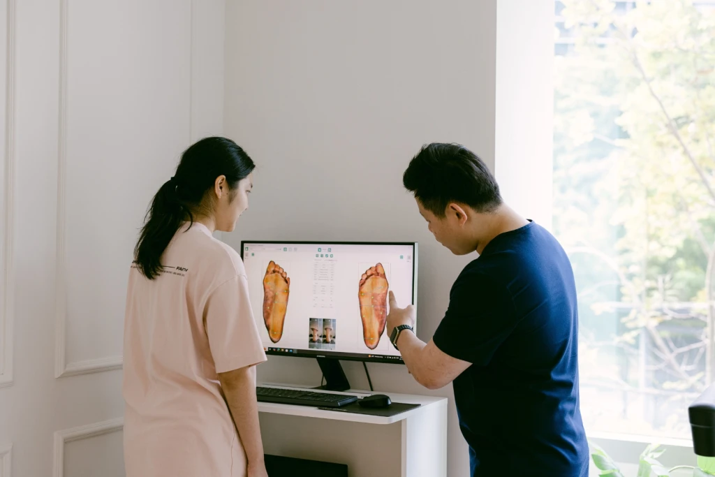Straits Podiatry podiatrist reviewing a patient's digital foot assessment on screen before recommending custom orthotics in Singapore