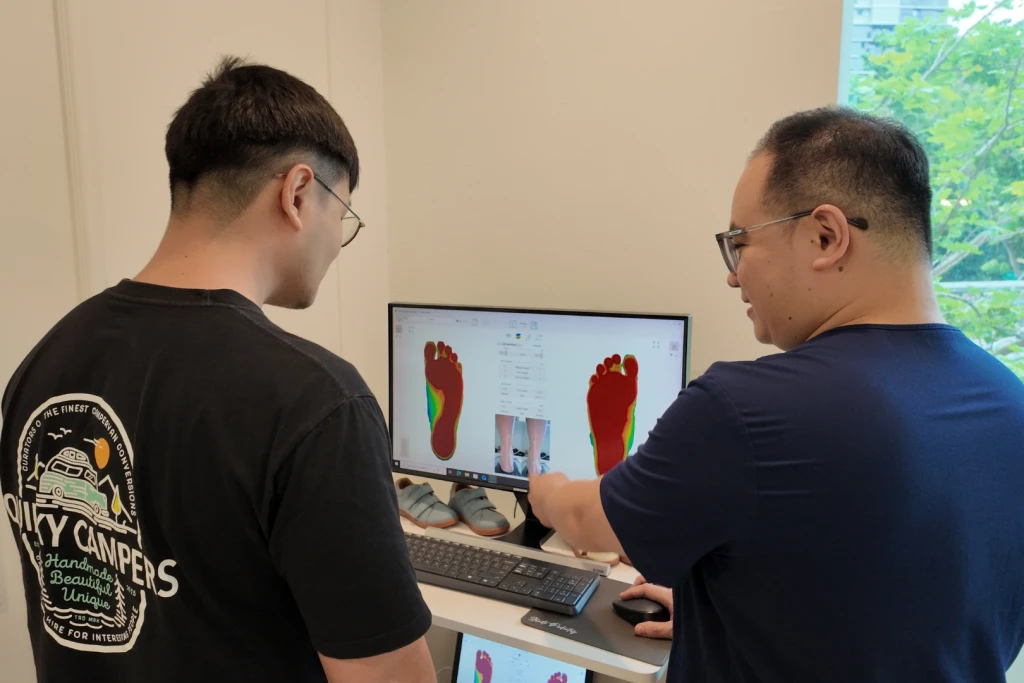 Podiatrist showing a patient a digital foot pressure scan on screen during an overpronation assessment at Straits Podiatry Singapore