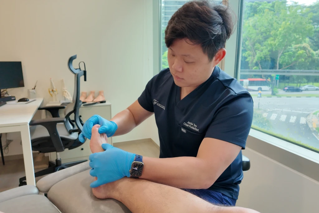 Mr Jackie Tey, Chief Podiatrist at Straits Podiatry, examining a patient's foot during a podiatry assessment in Singapore