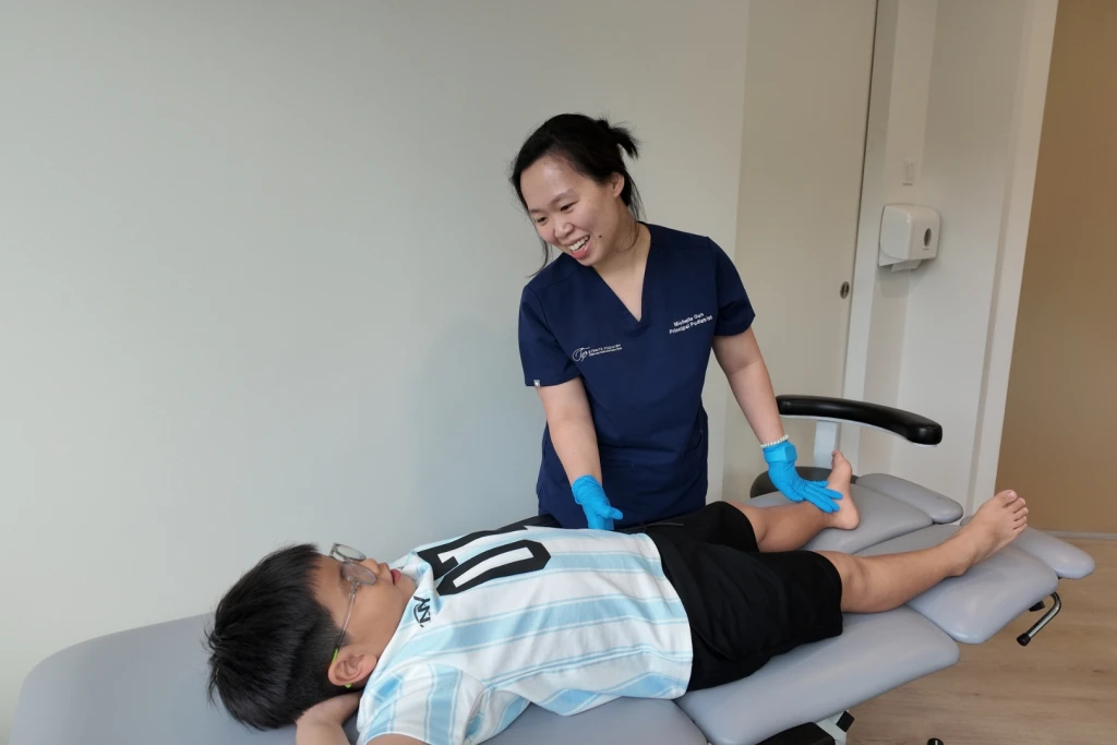 Straits Podiatry podiatrist assessing a school-aged boy's leg and hip rotation on a clinic bed, a rotational check used when a child in-toes
