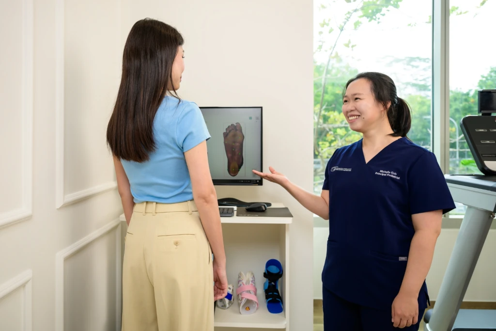 Straits Podiatry podiatrist Michelle Goh showing a patient her 3D foot scan results during a biomechanics assessment