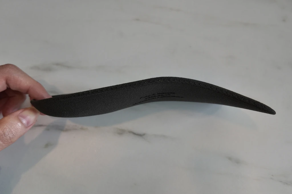 Side view of the rigid contoured shell of a custom insole, showing the supportive arch curve